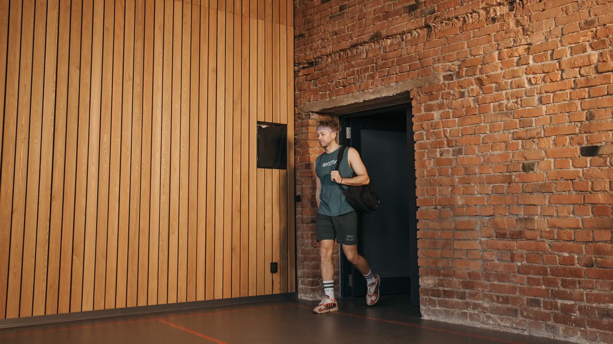 A sporty man leaving a brick-walled sports hall, embodying active lifestyle and fitness.